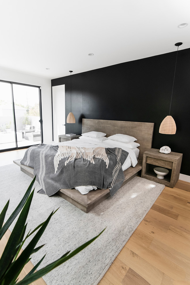Modelo de dormitorio principal costero grande sin chimenea con paredes blancas, suelo de madera clara y suelo marrón