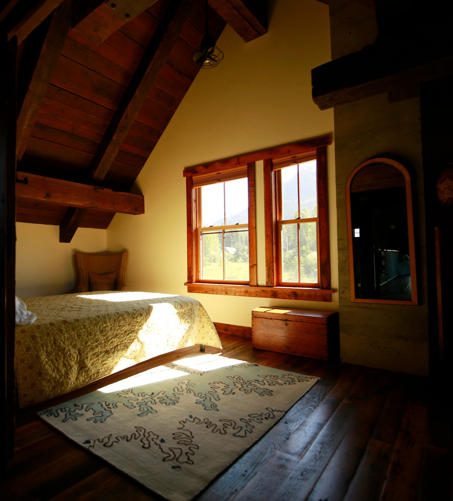 Großes Uriges Schlafzimmer im Loft-Style mit gelber Wandfarbe, braunem Holzboden, Kamin, Kaminumrandung aus Beton und braunem Boden in Sonstige