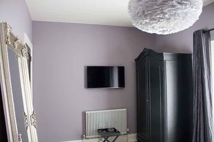 This is an example of a medium sized contemporary guest bedroom in Cardiff with purple walls, carpet, no fireplace and grey floors.