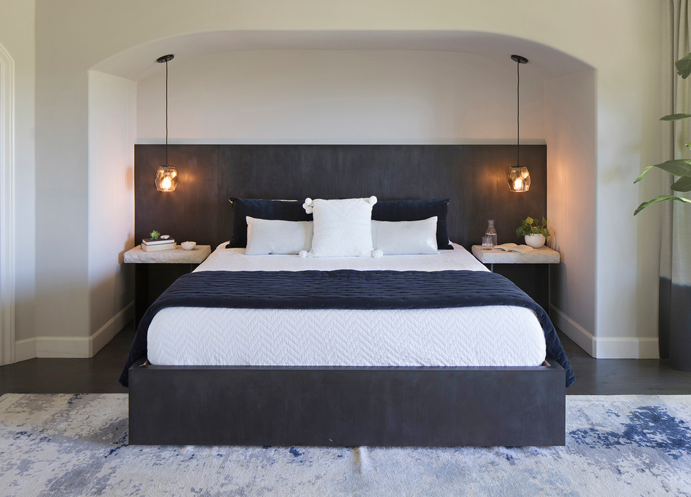 Großes Modernes Hauptschlafzimmer mit beiger Wandfarbe, dunklem Holzboden, Kamin, verputzter Kaminumrandung und grauem Boden in Orange County