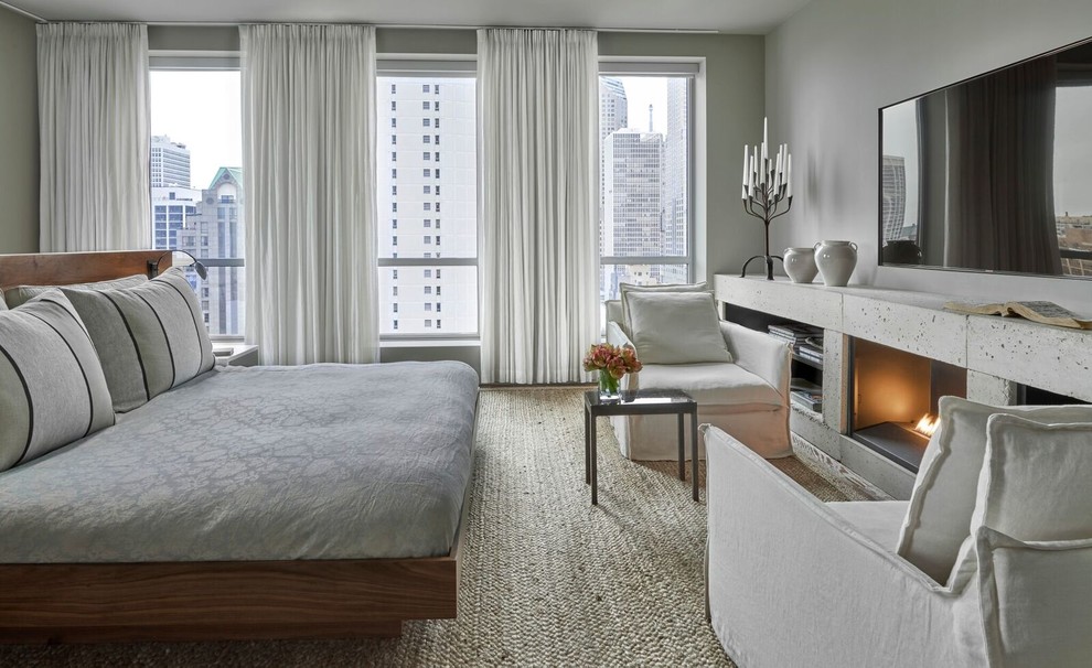Photo of a large contemporary master bedroom in Chicago with grey walls, a concrete fireplace surround, carpet and a standard fireplace.