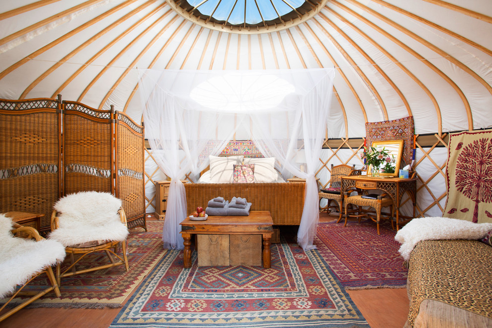 Ejemplo de dormitorio principal tropical pequeño sin chimenea con paredes blancas y suelo marrón