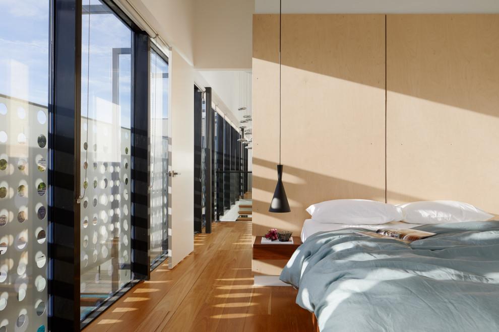 Ispirazione per una camera degli ospiti minimal di medie dimensioni con pareti beige, pavimento in legno massello medio, pavimento marrone e pannellatura