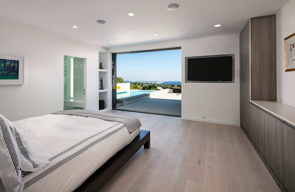 Modelo de dormitorio principal contemporáneo de tamaño medio con paredes blancas, suelo de madera clara y suelo beige