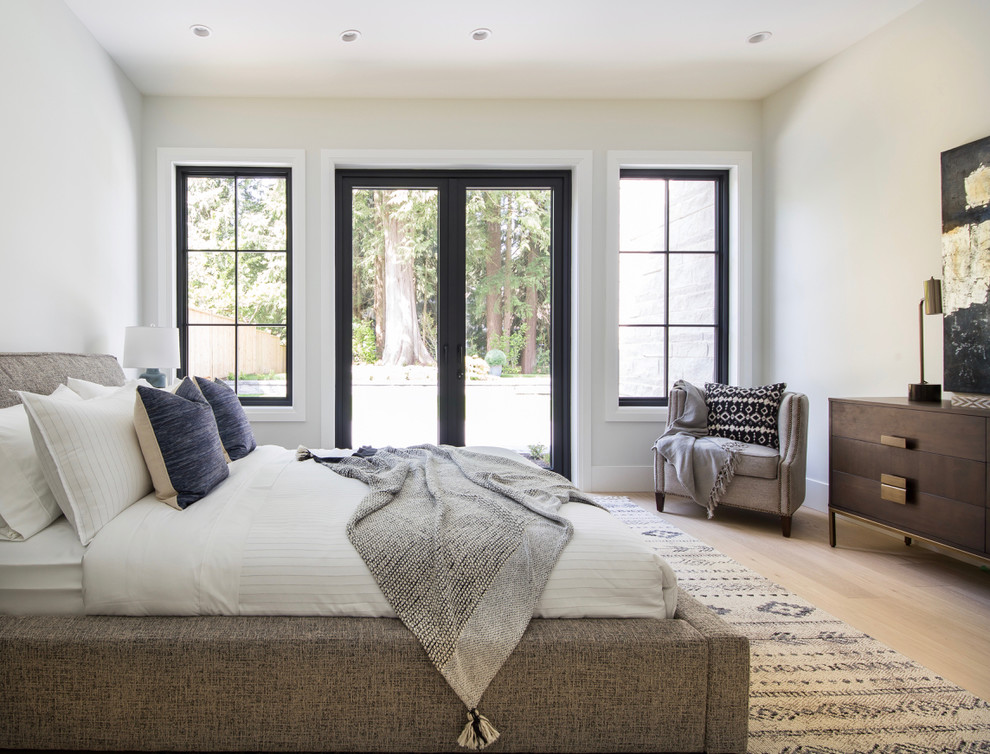 Immagine di una camera degli ospiti design con pareti bianche, parquet chiaro e pavimento beige
