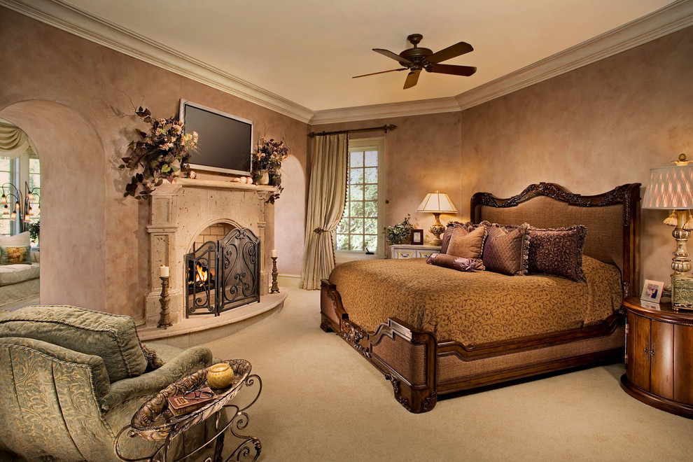 Large tuscan master carpeted bedroom photo in Atlanta with beige walls, a standard fireplace and a plaster fireplace