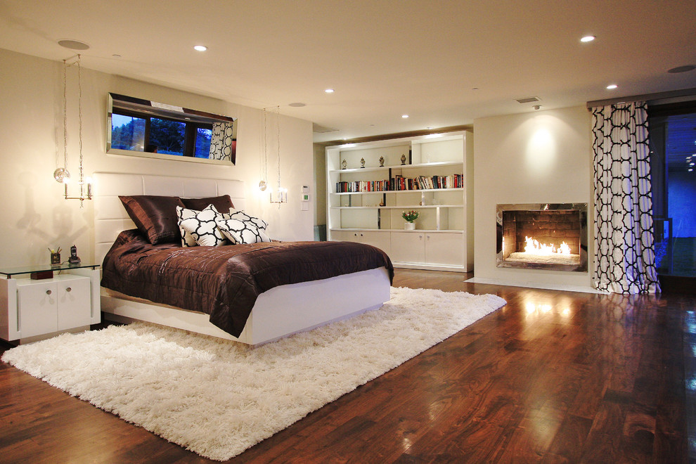 Trendy dark wood floor bedroom photo in Los Angeles with white walls and a standard fireplace