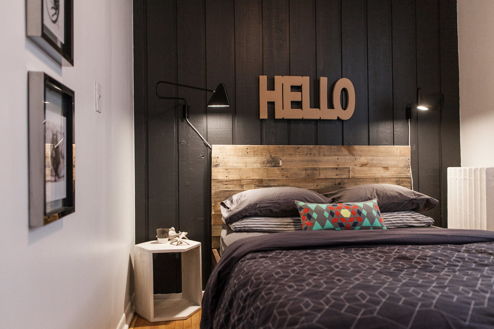 Immagine di una piccola camera da letto con pareti nere e parquet chiaro