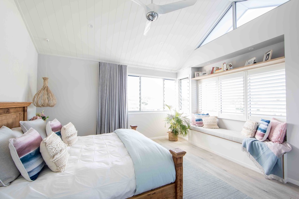 ゴールドコーストにある中くらいなビーチスタイルのおしゃれなロフト寝室 (白い壁、塗装フローリング、グレーの床)