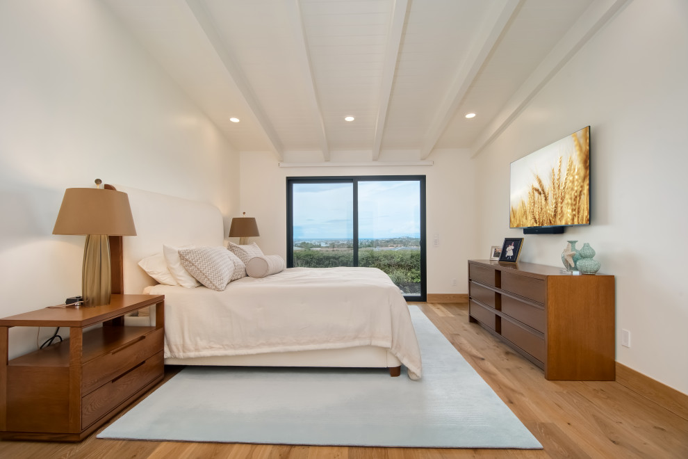 Ejemplo de dormitorio principal actual de tamaño medio con paredes blancas, suelo beige y vigas vistas