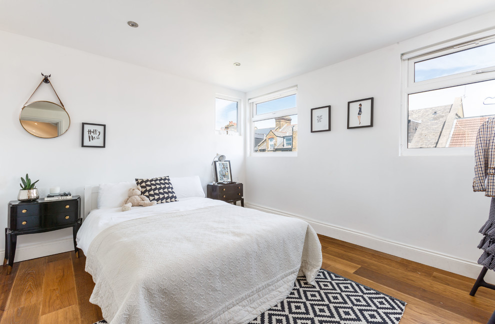 Imagen de dormitorio escandinavo de tamaño medio con paredes blancas, suelo de madera en tonos medios y suelo marrón