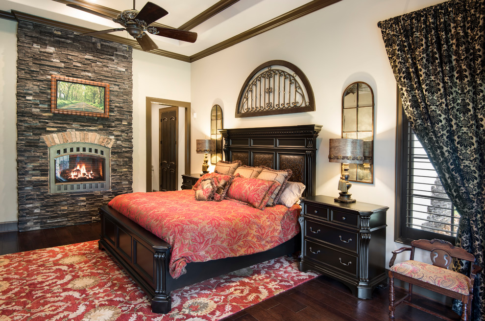 Photo of a classic bedroom in Houston with white walls, dark hardwood flooring, a standard fireplace, a stone fireplace surround and brown floors.