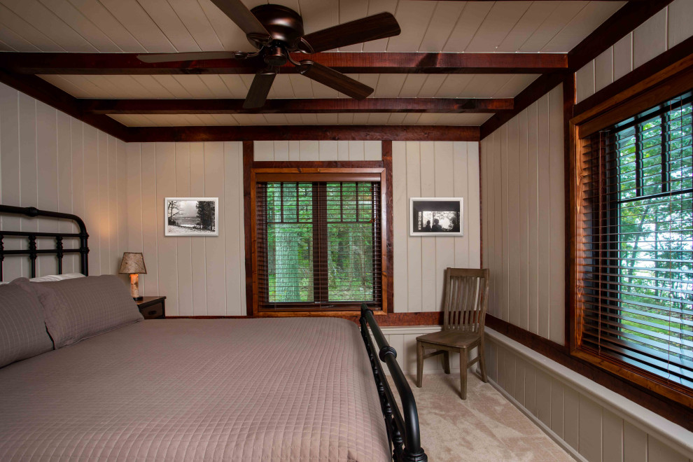Immagine di una grande camera degli ospiti stile rurale con pareti beige, moquette, pavimento beige, travi a vista e pannellatura