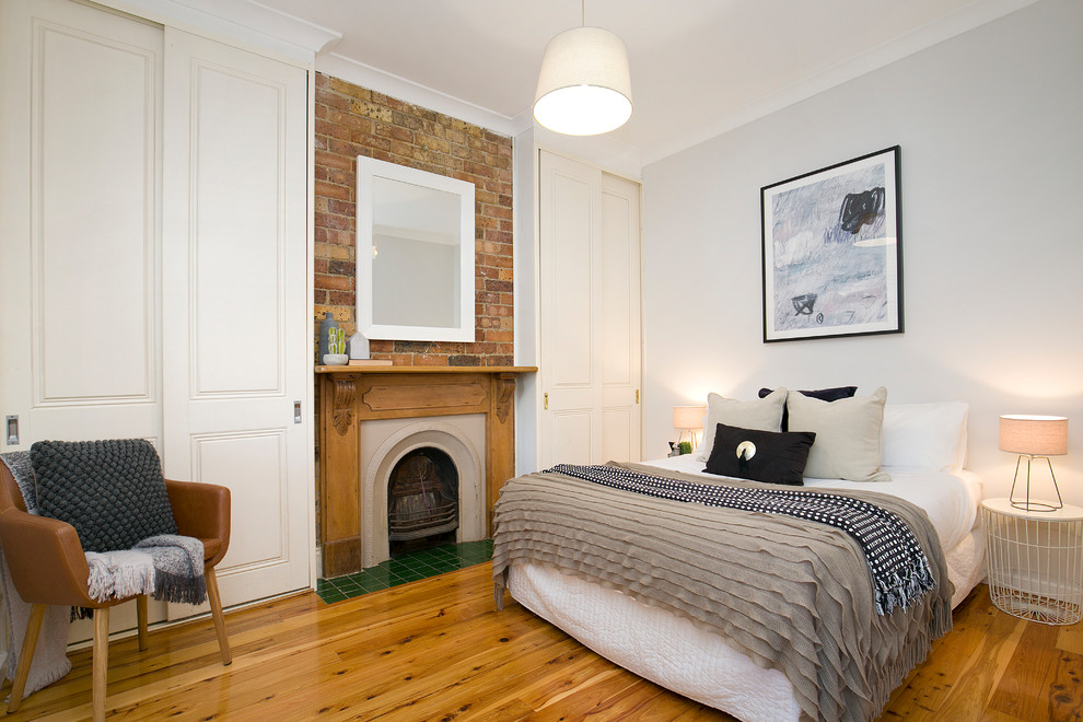 Hauptschlafzimmer mit weißer Wandfarbe, braunem Holzboden, Kamin, Kaminumrandung aus Holz und braunem Boden in Sydney