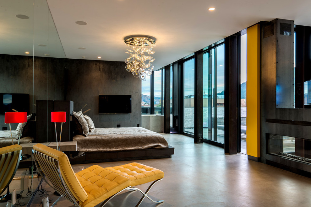 Modernes Hauptschlafzimmer mit grauer Wandfarbe, Betonboden, Tunnelkamin, grauem Boden und Kaminumrandung aus Beton in Sonstige