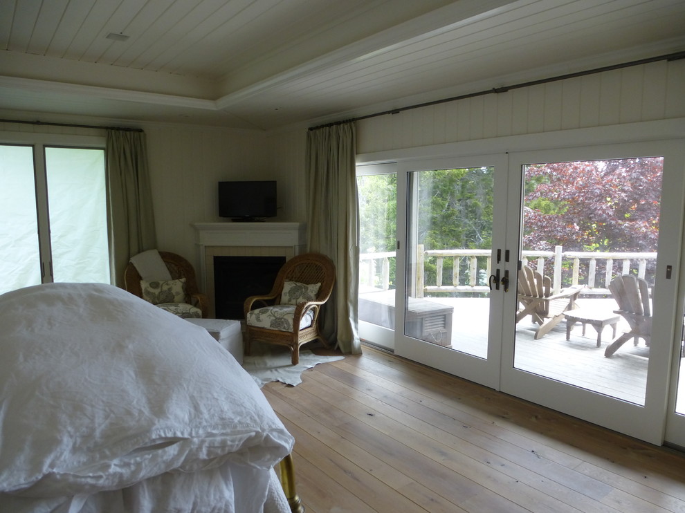 Foto di una grande camera da letto tradizionale con pareti bianche, parquet chiaro, camino ad angolo e cornice del camino piastrellata