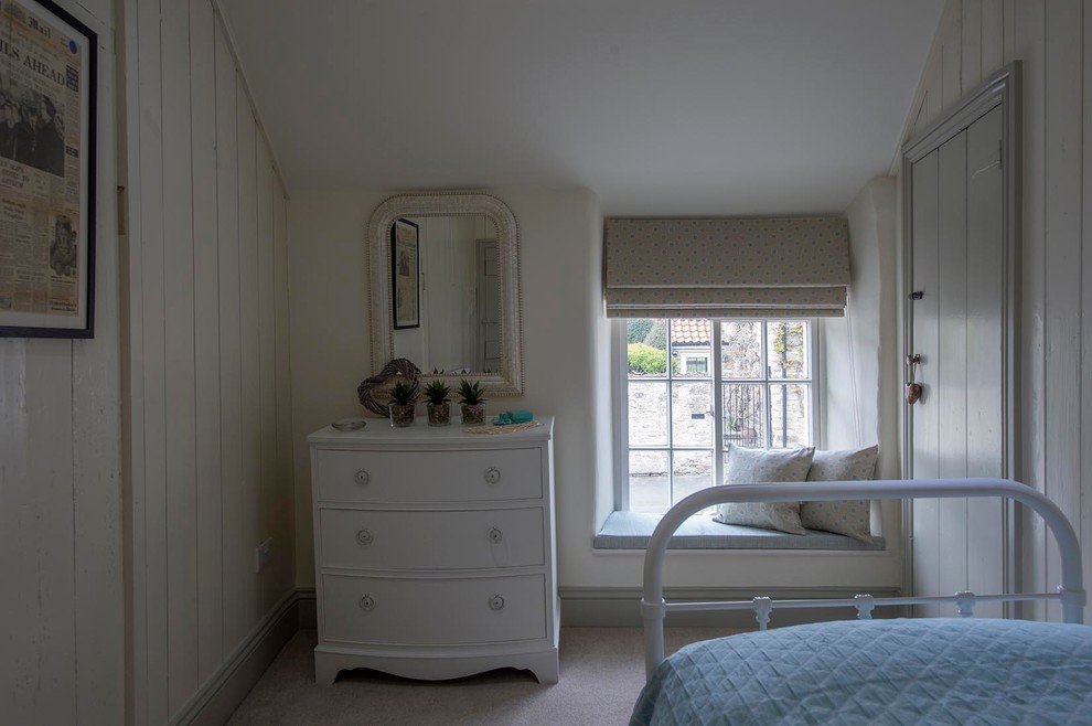 Diseño de habitación de invitados de estilo de casa de campo pequeña con paredes beige, moqueta, marco de chimenea de metal y suelo beige