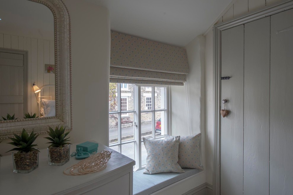 Ejemplo de habitación de invitados de estilo de casa de campo pequeña con paredes beige, moqueta, marco de chimenea de metal y suelo beige