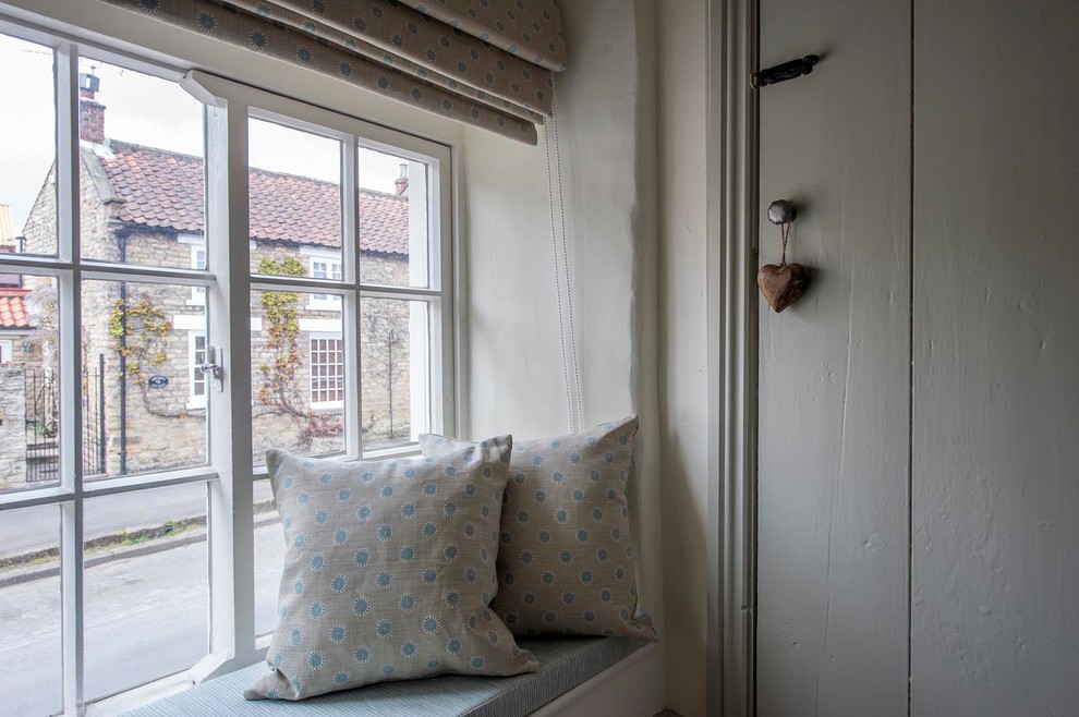 Modelo de habitación de invitados campestre pequeña con paredes beige, moqueta, marco de chimenea de metal y suelo beige