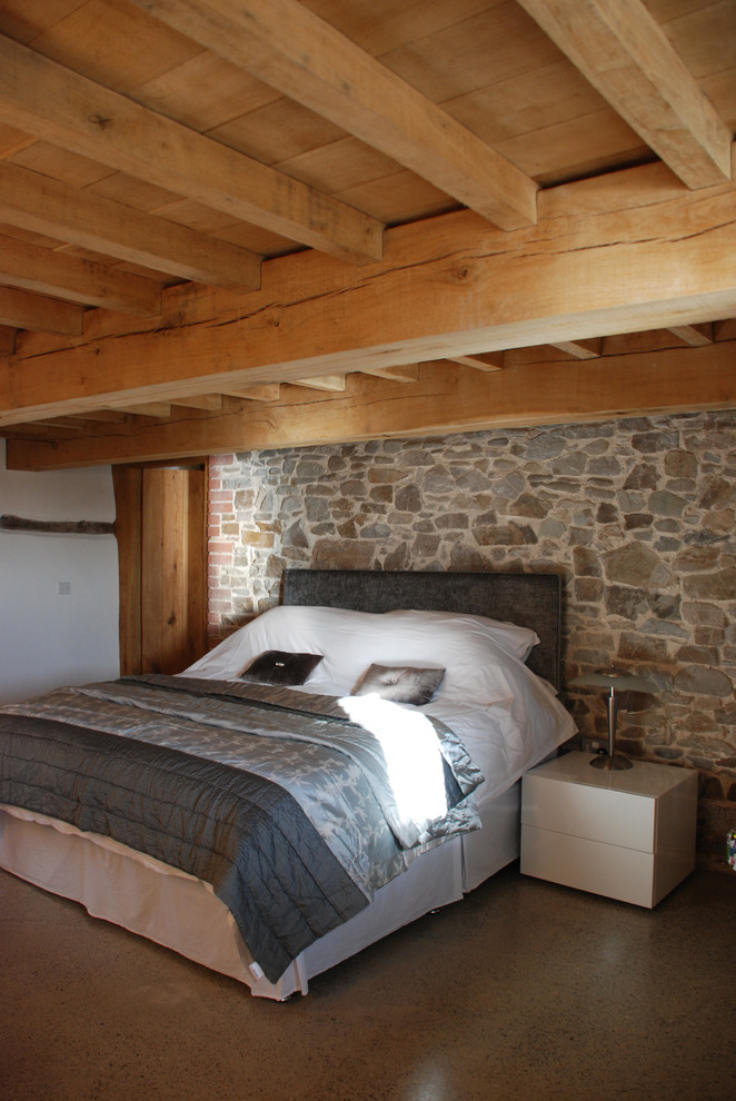 Diseño de habitación de invitados rural extra grande sin chimenea con paredes grises, suelo de cemento, suelo marrón y vigas vistas