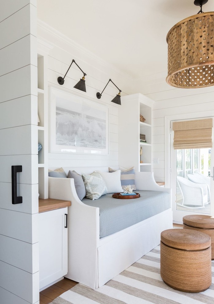 Ispirazione per una camera degli ospiti costiera con pareti bianche, pavimento in legno massello medio e pavimento marrone