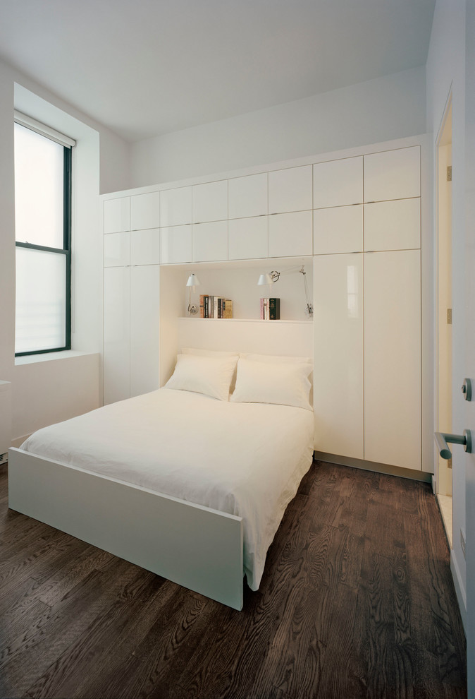 Diseño de dormitorio principal minimalista de tamaño medio con paredes blancas, suelo de madera oscura y suelo marrón