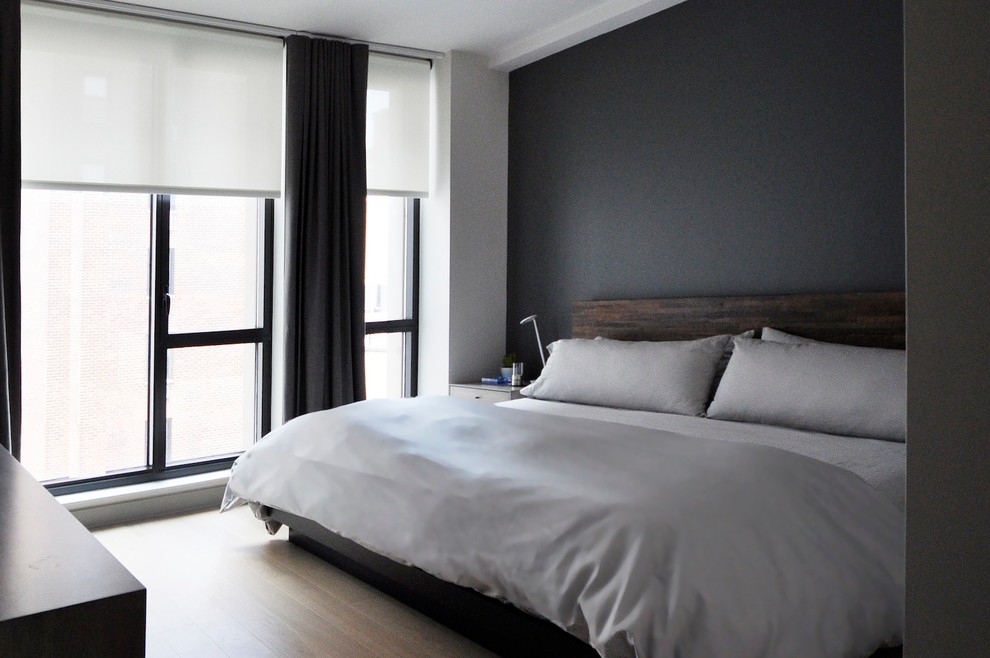 Medium sized contemporary master and grey and silver bedroom in New York with grey walls and light hardwood flooring.