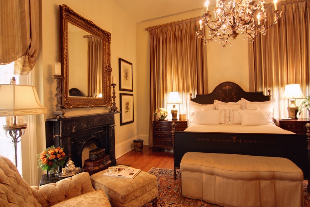 На фото: большая гостевая спальня (комната для гостей) в классическом стиле с бежевыми стенами, темным паркетным полом, стандартным камином и фасадом камина из штукатурки с