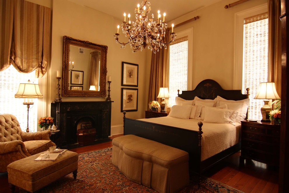 Пример оригинального дизайна: большая гостевая спальня (комната для гостей) в классическом стиле с бежевыми стенами, темным паркетным полом, стандартным камином и фасадом камина из штукатурки