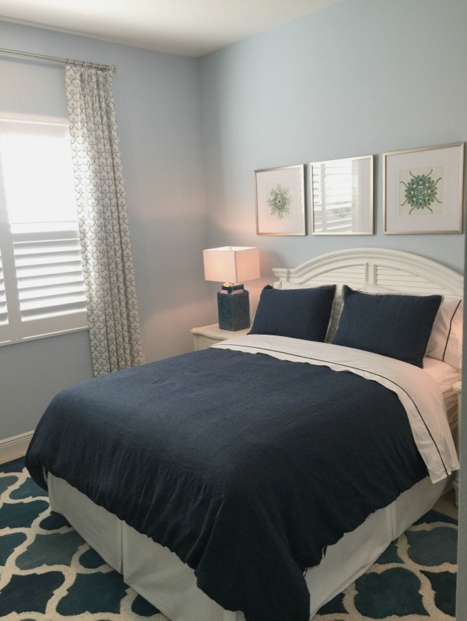 Exemple d'une chambre d'amis bord de mer de taille moyenne avec un mur bleu, un sol en carrelage de céramique et un sol beige.