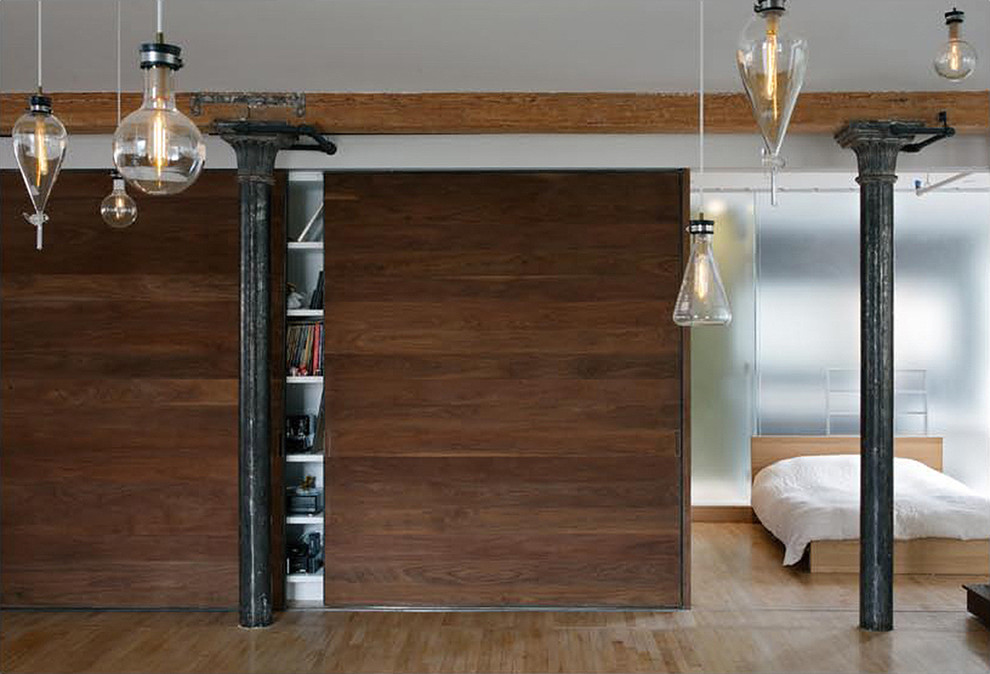 ニューヨークにある中くらいなインダストリアルスタイルのおしゃれな客用寝室 (茶色い壁、無垢フローリング、暖炉なし)