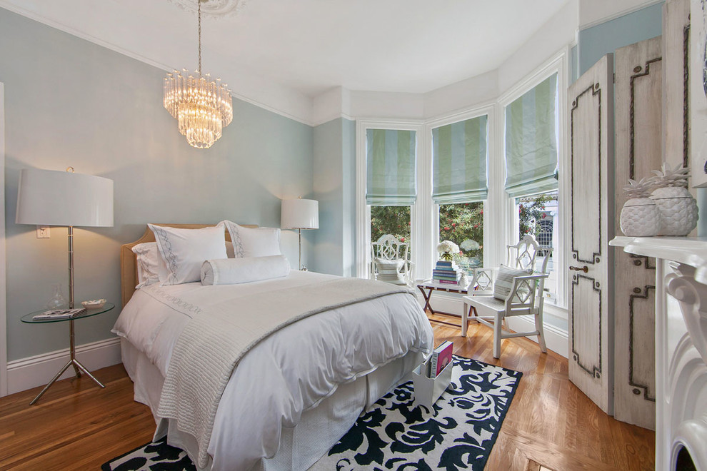 Imagen de dormitorio principal clásico grande con paredes azules, todas las chimeneas, suelo de madera oscura, marco de chimenea de madera y suelo marrón