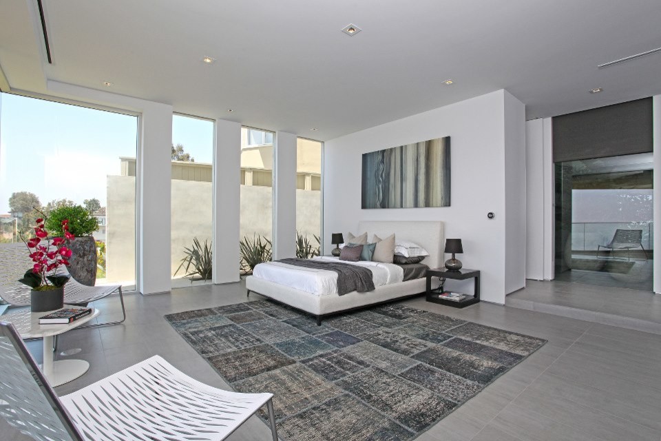 На фото: огромная хозяйская, серо-белая спальня в стиле модернизм с белыми стенами, серым полом и многоуровневым потолком