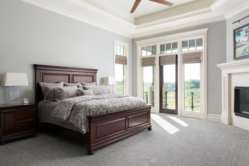 На фото: большая хозяйская спальня в стиле рустика с серыми стенами, ковровым покрытием, угловым камином, фасадом камина из дерева и серым полом с
