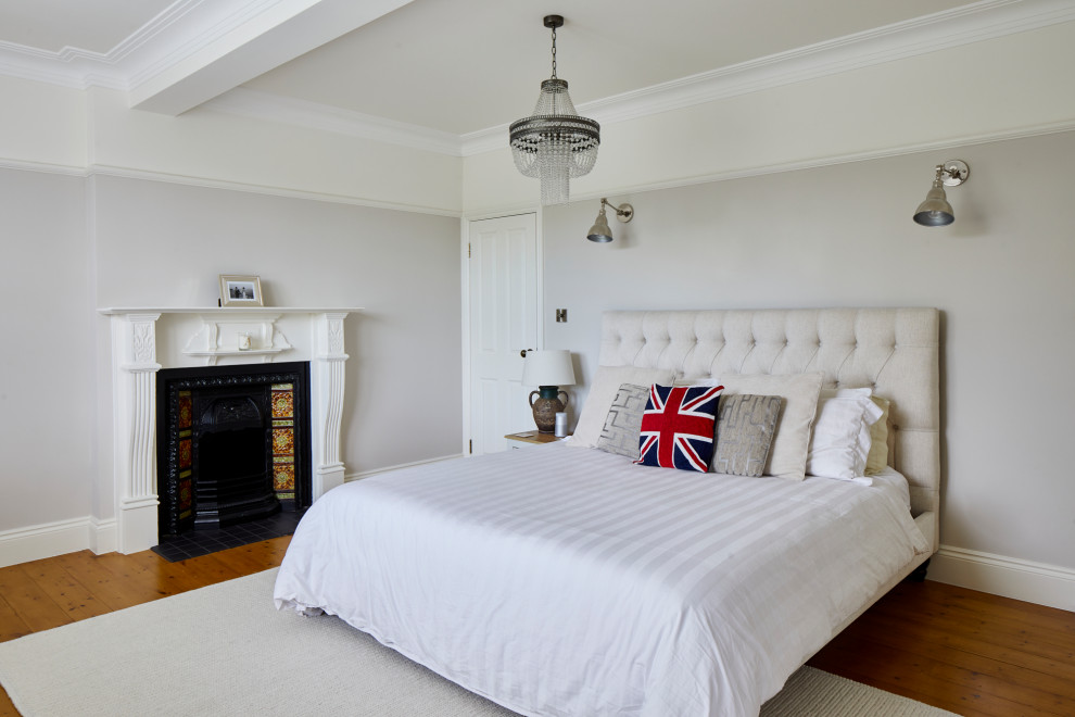 Medium sized traditional master and grey and white bedroom in London with grey walls, medium hardwood flooring, a standard fireplace, a plastered fireplace surround, brown floors and a coffered ceiling.