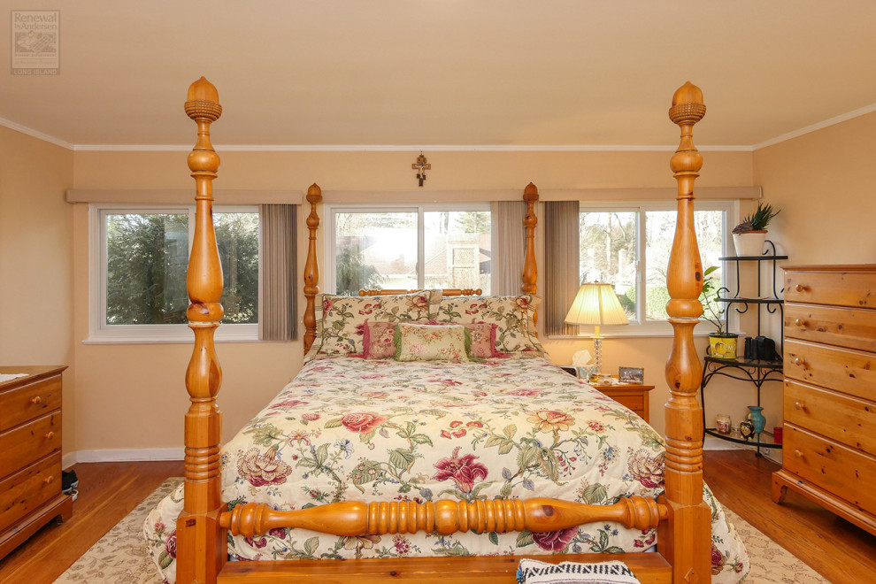 Foto de dormitorio principal de tamaño medio sin chimenea con parades naranjas, suelo de madera en tonos medios y suelo multicolor
