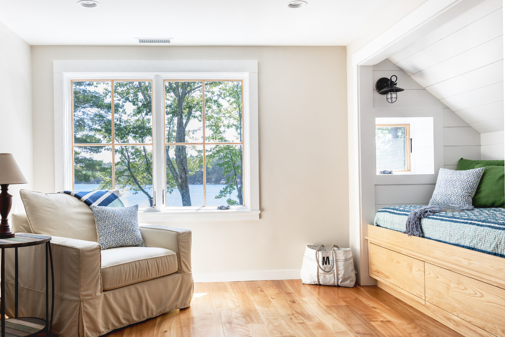 Modelo de habitación de invitados costera de tamaño medio con paredes blancas, suelo de madera clara y suelo marrón