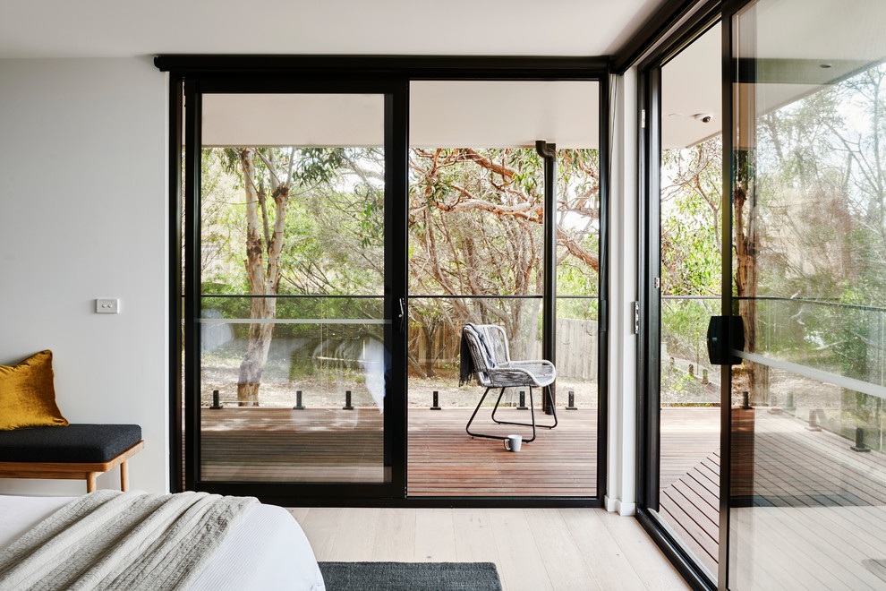 Cette image montre une chambre parentale minimaliste de taille moyenne avec un mur blanc, parquet clair et un sol marron.