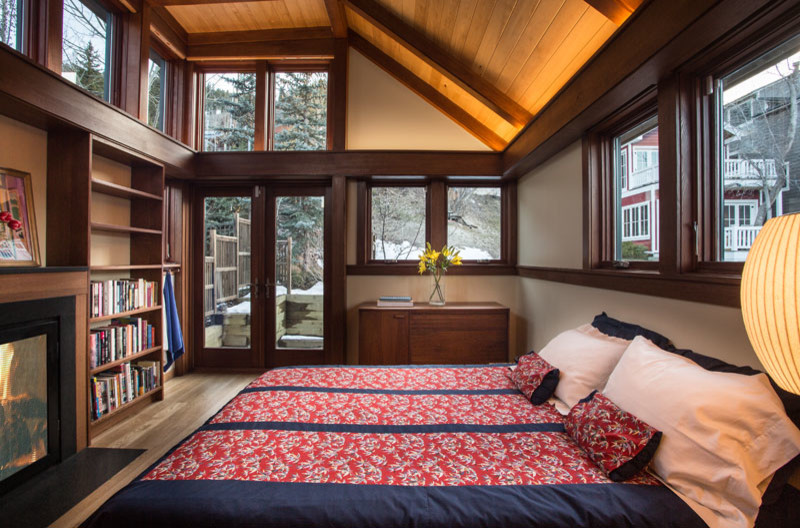 Kleines Hauptschlafzimmer mit weißer Wandfarbe, braunem Holzboden, Kamin und Kaminumrandung aus Holz in Salt Lake City