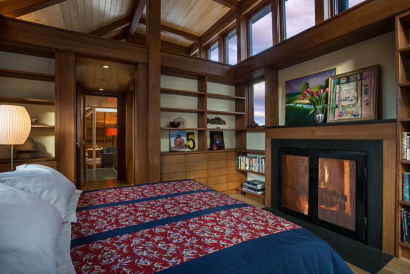 Cette photo montre une chambre parentale avec un mur blanc, un sol en bois brun, une cheminée standard et un manteau de cheminée en bois.