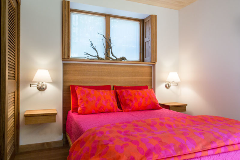 Foto de habitación de invitados pequeña con paredes blancas, suelo de madera en tonos medios, todas las chimeneas y marco de chimenea de piedra