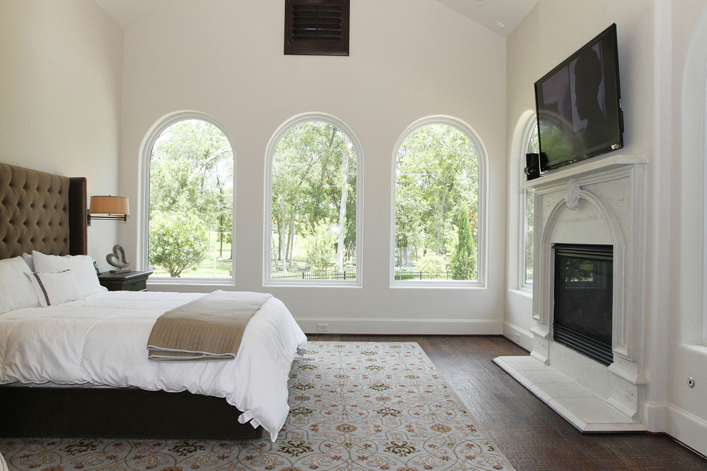 Medelhavsstil inredning av ett sovrum, med vita väggar, mörkt trägolv, en standard öppen spis och brunt golv