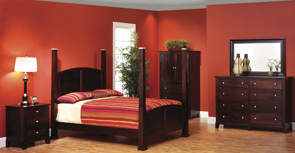Modelo de dormitorio grande sin chimenea con paredes rojas y suelo de madera clara