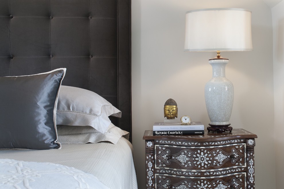 This is an example of a classic grey and brown bedroom in New York with white walls.