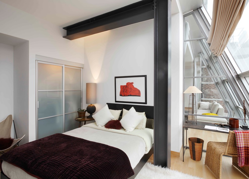Photo of a contemporary bedroom in New York with white walls and light hardwood flooring.