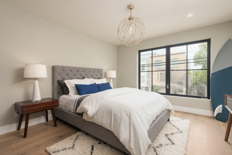 Imagen de dormitorio contemporáneo de tamaño medio sin chimenea con paredes grises, suelo de madera clara y suelo marrón