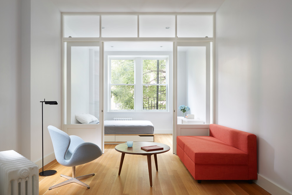 Kleines Skandinavisches Schlafzimmer mit weißer Wandfarbe und braunem Holzboden in New York