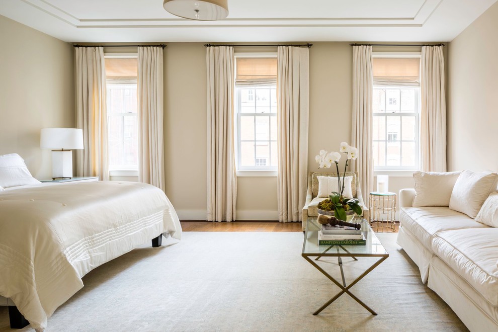 Idée de décoration pour une chambre parentale tradition de taille moyenne avec un mur beige et un sol en bois brun.