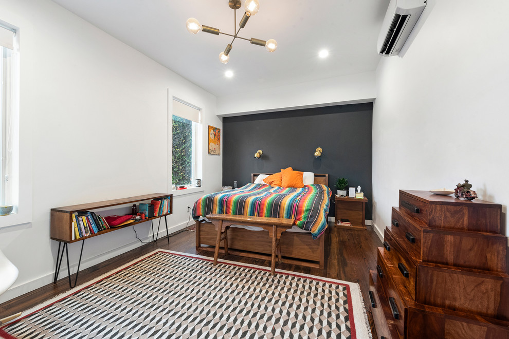 Modernes Schlafzimmer mit weißer Wandfarbe, dunklem Holzboden und braunem Boden in New York