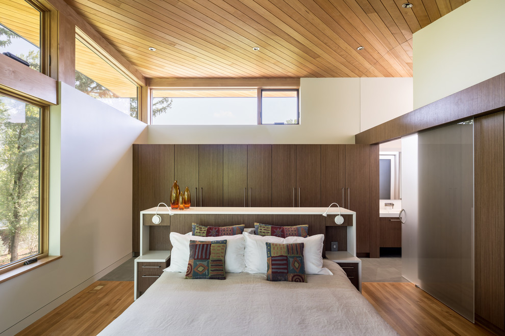 Ispirazione per una camera matrimoniale design di medie dimensioni con pareti bianche, pavimento in legno massello medio e pavimento marrone